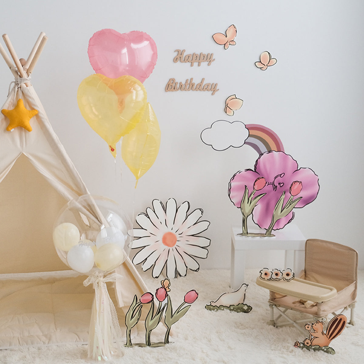 A cozy children's birthday setup with a small fabric tent adorned with a star, balloons in pink, yellow, and white, and colorful Eanjia Rainbow Tulip Garden Cutouts | 16pc Watercolor Daisy & Squirrel Decor | Baby Shower & Birthday Props. A “Happy Birthday” sign decorates the wall, with a small chair and plush toys nearby.